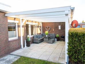 A covered patio area with a brick wall, a heart-shaped decoration, and outdoor furniture.