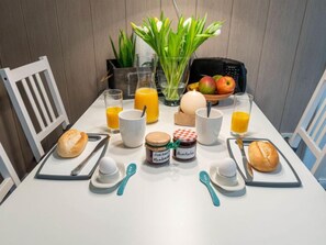 Uma mesa de café da manhã com pão, ovos, geleia e suco.
