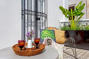Enjoy a romantic meal for two in this serene outdoor seating area, complete with a round table, woven placemat, and a beautiful potted plant.