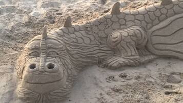Una escultura de arena de un dinosaurio con una cabeza grande y dos cuernos.