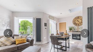 Un salón espacioso con un sofá gris, una mesa de comedor con sillas y una zona de cocina al fondo.