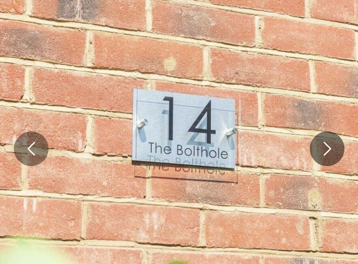 Eine Ziegelmauer mit einem Hausnummernschild, auf dem '14 The Bolthouse' steht.