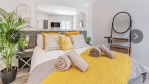 Una habitación de hotel moderna con una cama, un espejo grande y una planta en maceta.