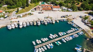 An aerial view of a marina with numerous boats docked, a pier extending into the water, and a building with a red roof in the background. - Villa Krnica in Krnica (Marcana)