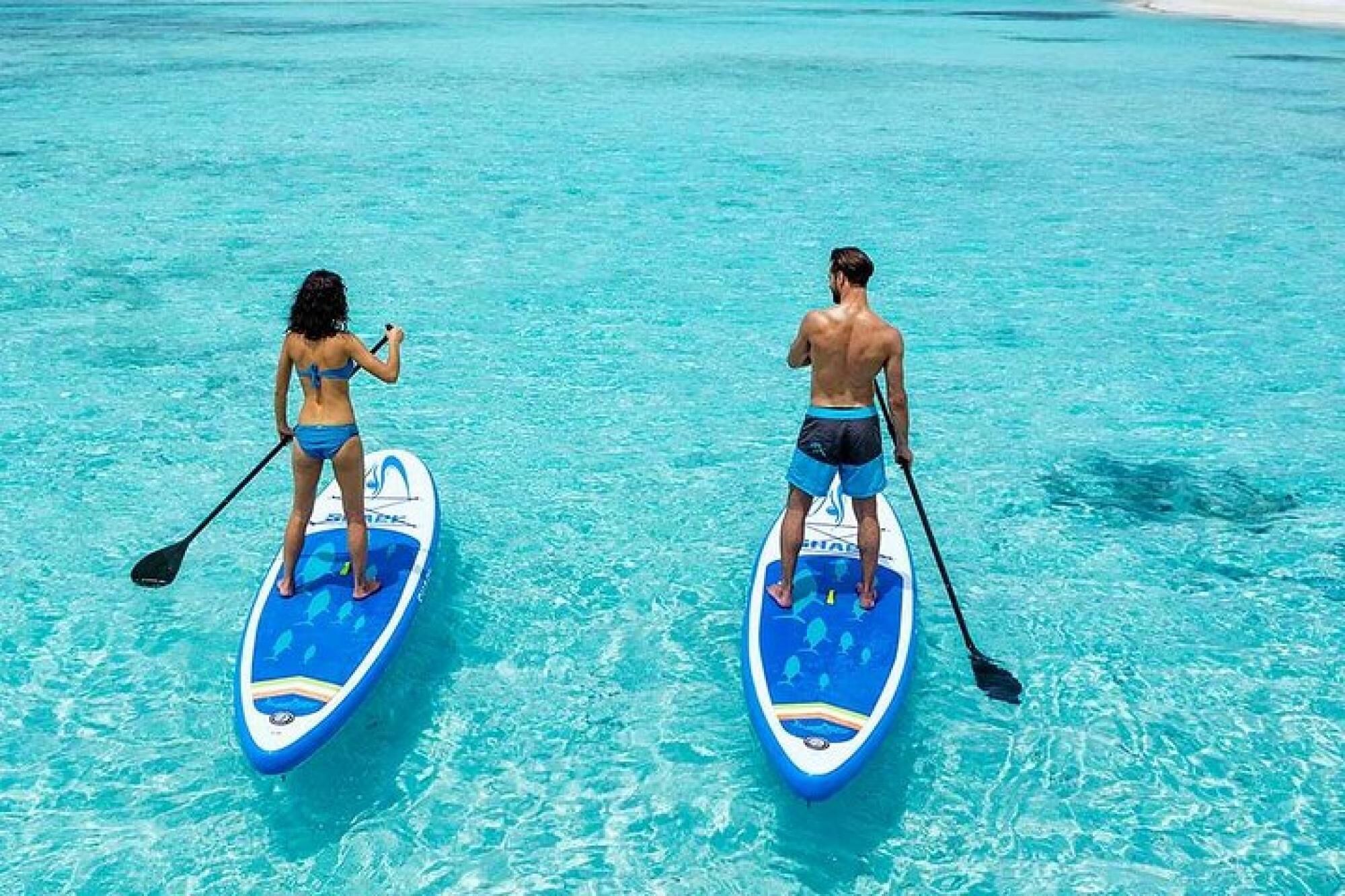 Deux personnes pratiquent le paddle sur une étendue d’eau d’un bleu limpide.