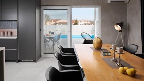 A modern kitchen with a dining area, a view of a swimming pool, and a balcony with outdoor seating. - Villa Ovis in Peresiji (Svetvincenat)