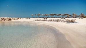 A beach with clear water, sun loungers, and umbrellas. - Villa Ovis in Peresiji (Svetvincenat)