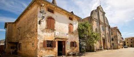 A rustic building with a traditional architectural style, featuring a prominent tower and a small entrance.