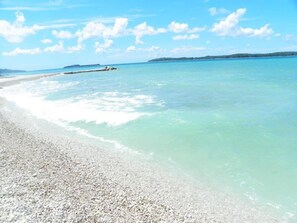 Ein Strand mit klarem türkisblauem Wasser und einem Kiesstrand.