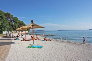 Ein Strand mit Sonnenschirmen und Menschen, die sich sonnen.