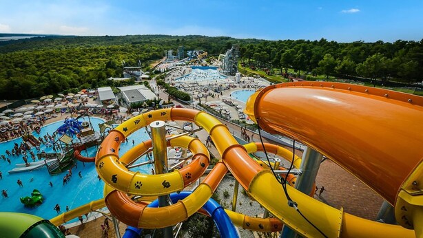 A water park with multiple slides and pools, surrounded by lush greenery and a clear sky. - Villa Ovis in Peresiji (Svetvincenat)