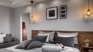 A modern bedroom with a large bed, multiple pillows, a wooden headboard, and two wall-mounted pendant lights. - Villa Ovis in Peresiji (Svetvincenat)