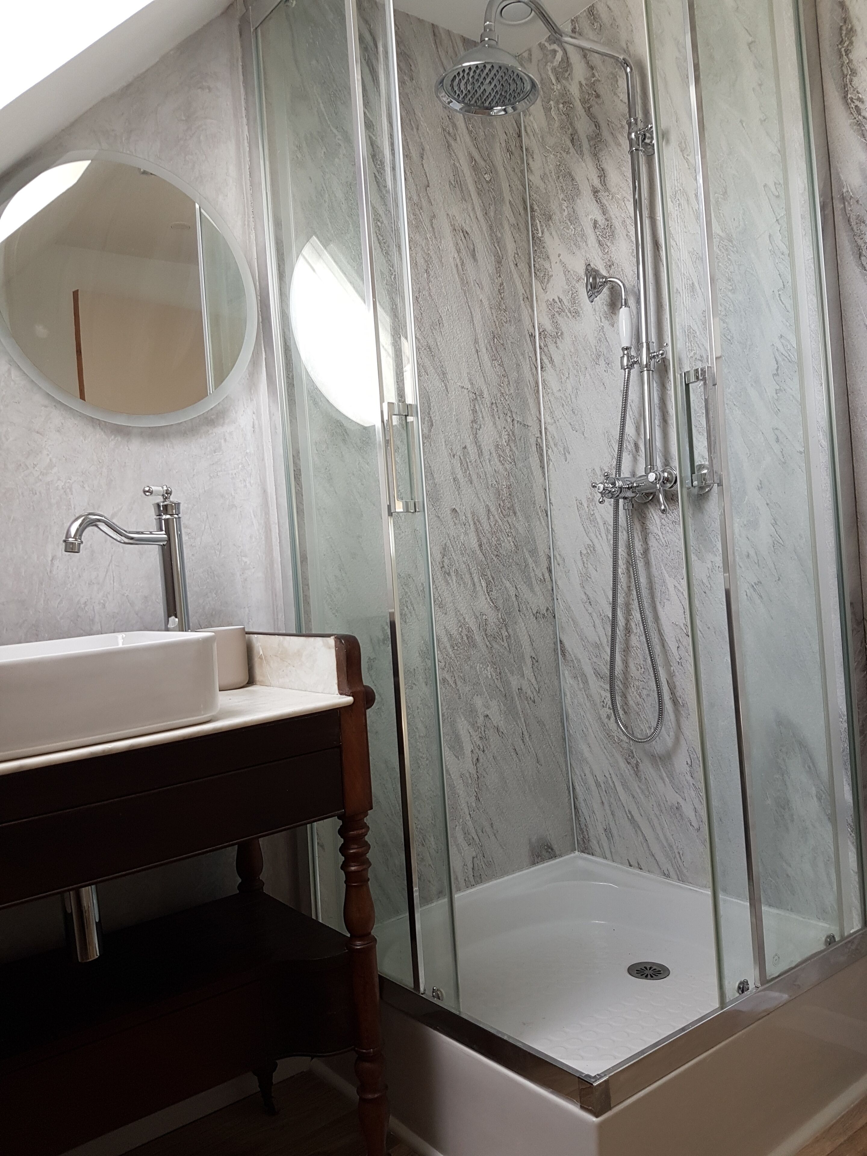 A bathroom with a glass-enclosed shower, a white sink, and a wooden vanity.