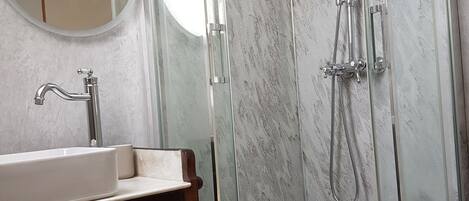A bathroom with a glass-enclosed shower, a white sink, and a wooden vanity.