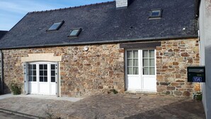 A stone building with two windows and a door, a stone roof, and a small sign with the number 156.