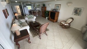 A living room with a sofa, chairs, a coffee table, and a TV stand. - 411 Mistle Cove - Spacious beachfront apartment with large ocean facing balcony (St Lawrence Gap)