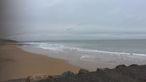 Una spiaggia con un litorale roccioso e un cielo nuvoloso.
