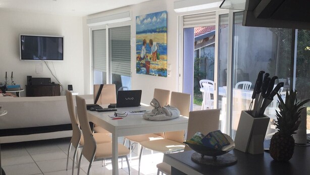 Una cucina moderna con zona pranzo, una TV a schermo piatto montata a parete e un quadro sopra il tavolo.