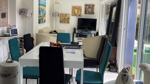 Un soggiorno moderno con zona pranzo, televisione a schermo piatto e opere d'arte alle pareti.