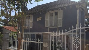 Un edificio a due piani con facciata scura, persiane bianche e un cancello decorativo in metallo.