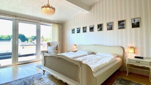 Une chambre à coucher avec un grand lit, une chaise, une table de chevet et un lustre.