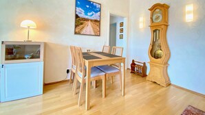 Un coin repas avec une table et des chaises en bois, une horloge et un tableau accroché au mur.