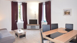 A modern living room with a sofa, a TV, a dining table with chairs, and a radiator. - Character house in a romantic setting "At the water's'edge (CHAMBON SUR VOUEIZE)