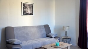 A grey sofa with cushions, a small wooden table with a decorative item, a lamp on a side table, and a framed picture on the wall. - Character house in a romantic setting "At the water's'edge (CHAMBON SUR VOUEIZE)