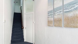 A staircase leading to a door marked with the number 1, a white wall, and a beach scene painting. - Family Apartment 2nd Floor (Blackpool)