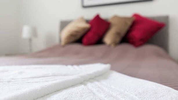A bed with a white blanket and multiple pillows in a hotel room. - Family Apartment 2nd Floor (Blackpool)