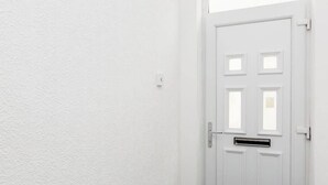 Une porte blanche, dotée d’une fente pour le courrier et d’une poignée, est encastrée dans un mur sobre.