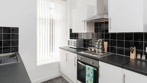 Une cuisine moderne avec des meubles blancs, un plan de travail noir et une fenêtre équipée de stores.