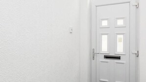 Eine weiße Tür mit Briefschlitz und Klinke.