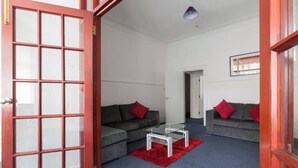 A modern living room with two grey sofas, red cushions, a red rug, and a white coffee table. - Two-Bedroom Apartment Ground Floor (Blackpool)