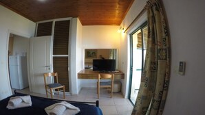 A bedroom with a bed, a desk with a chair, a television, and a wardrobe.