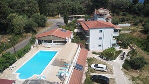 A residential property with a swimming pool, multiple buildings, and a parking area.