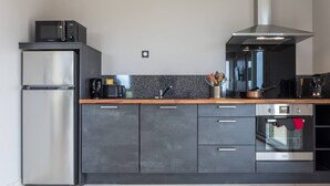 A modern kitchen with a stainless steel refrigerator, a microwave, a coffee maker, and an oven. - Tribord, apartment with terrace and sea view, parking (Saint-Côme-de-Fresné)
