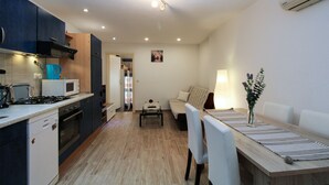 A compact kitchen with a stove, microwave, and toaster, a dining area with a table and chairs, and a living space with a sofa and a lamp. - Apartment 2178/55780 (Istria - Pula), 3000m from the beach (Pula)