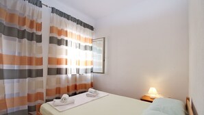 A neatly made bed with towels, a bedside lamp, and a window with curtains. - Apartment 2178/55780 (Istria - Pula), 3000m from the beach (Pula)