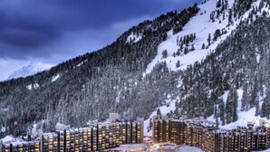 Une station de ski enneigée, avec de nombreux immeubles de grande hauteur, des pistes de ski et un télésiège.