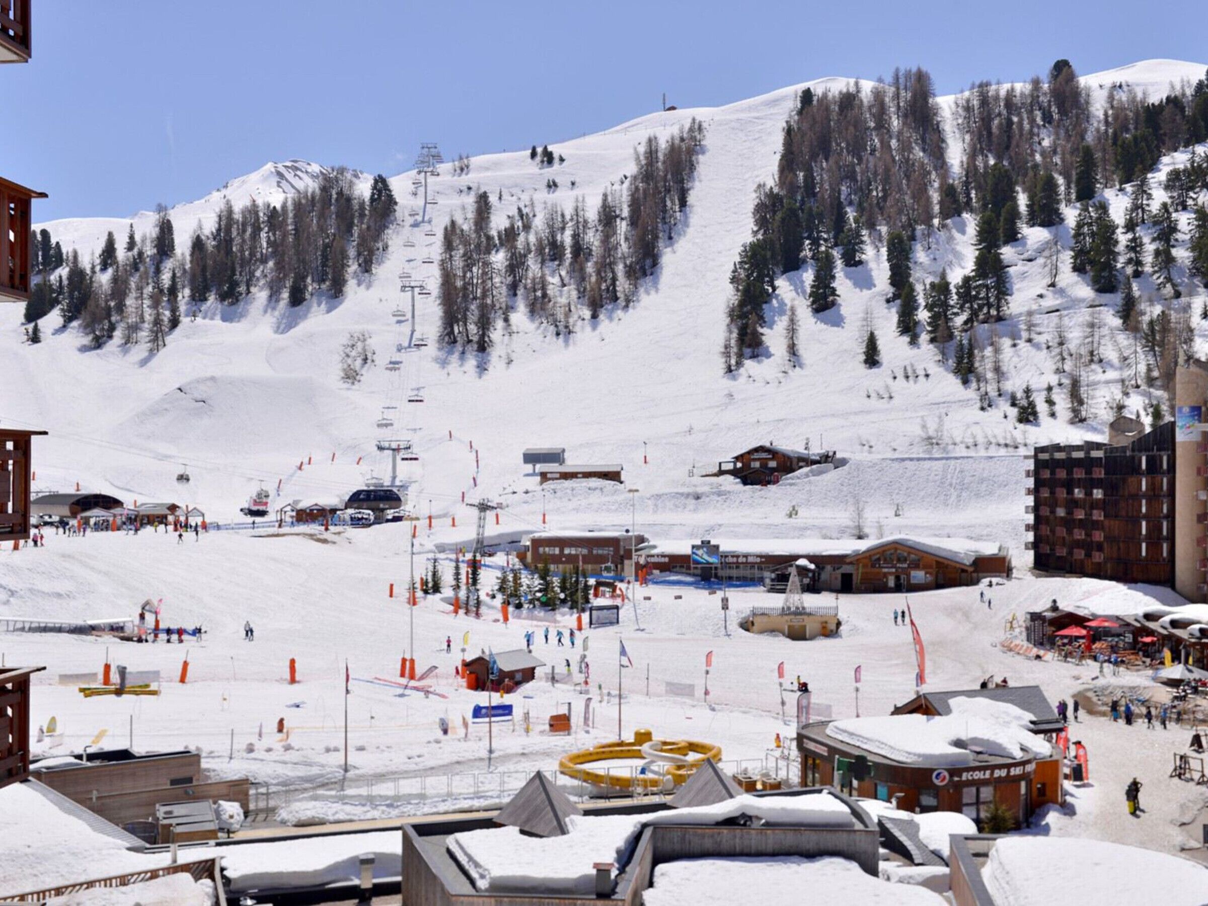 Une station de ski dotée d'un télésiège, de bâtiments et offrant un paysage enneigé.