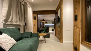 Una sala de estar moderna con un sofá verde, una mesita y una cocina al fondo.