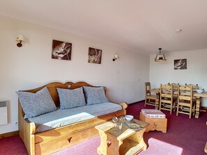 Un salón acogedor con un sofá de madera, una mesita de madera y un comedor con sillas y una mesa de madera.
