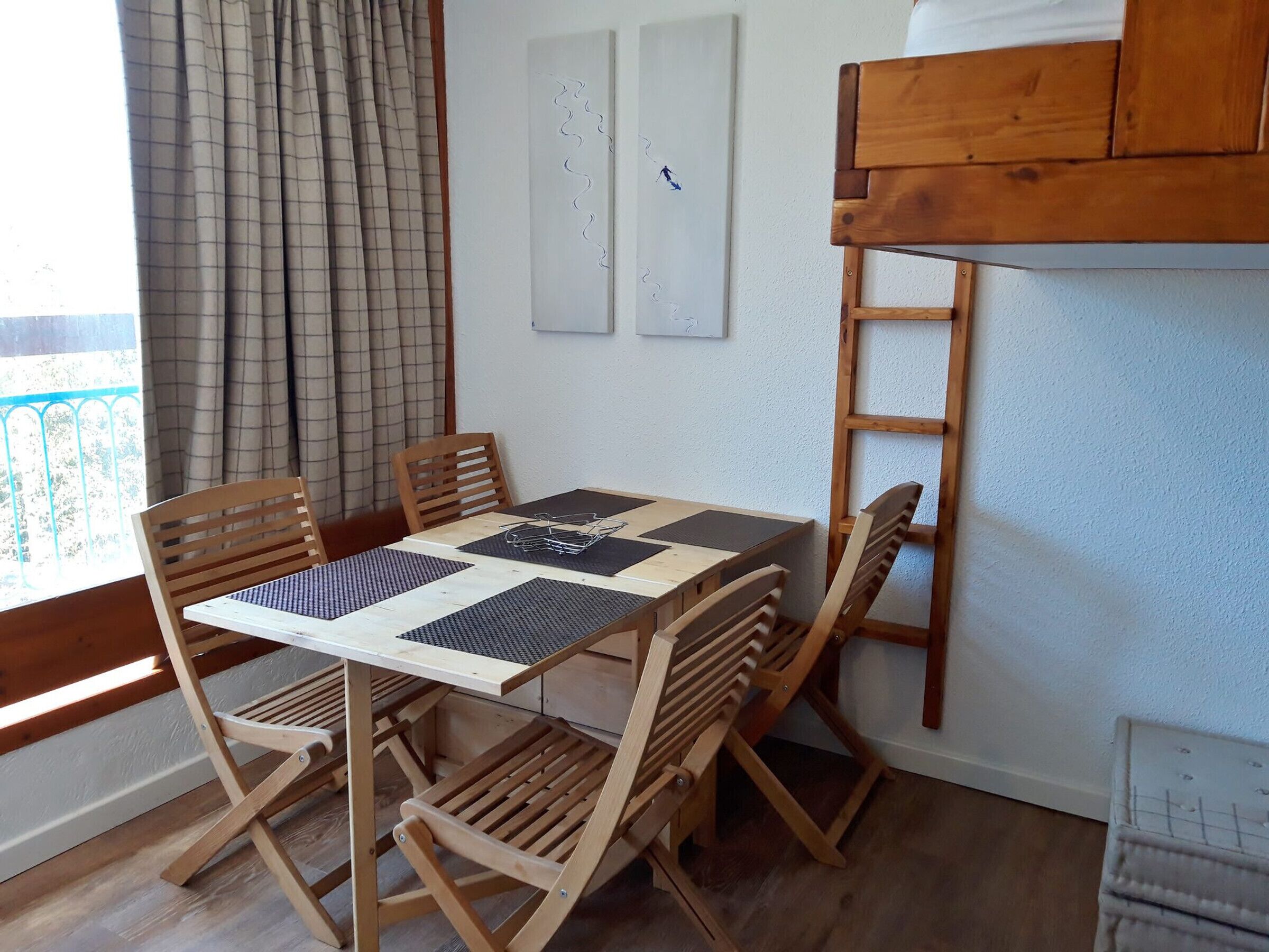 A dining area with a wooden table and chairs, a view of the outside, and a whiteboard on the wall.
