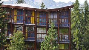 A multi-story building with balconies, surrounded by trees and mountains. - Renovated duplex in quiet area with balcony - 6/7 pers. (Les Arcs 1800)