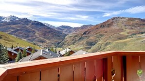 Eine gebirgige Landschaft mit Blick auf ein Tal und ferne Berggipfel.