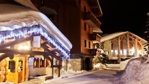 Ein schneebedecktes Gebäude mit einer Holzfassade und einem Steineingang.