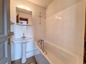 Un baño con un lavamanos blanco, una bañera y una ducha.