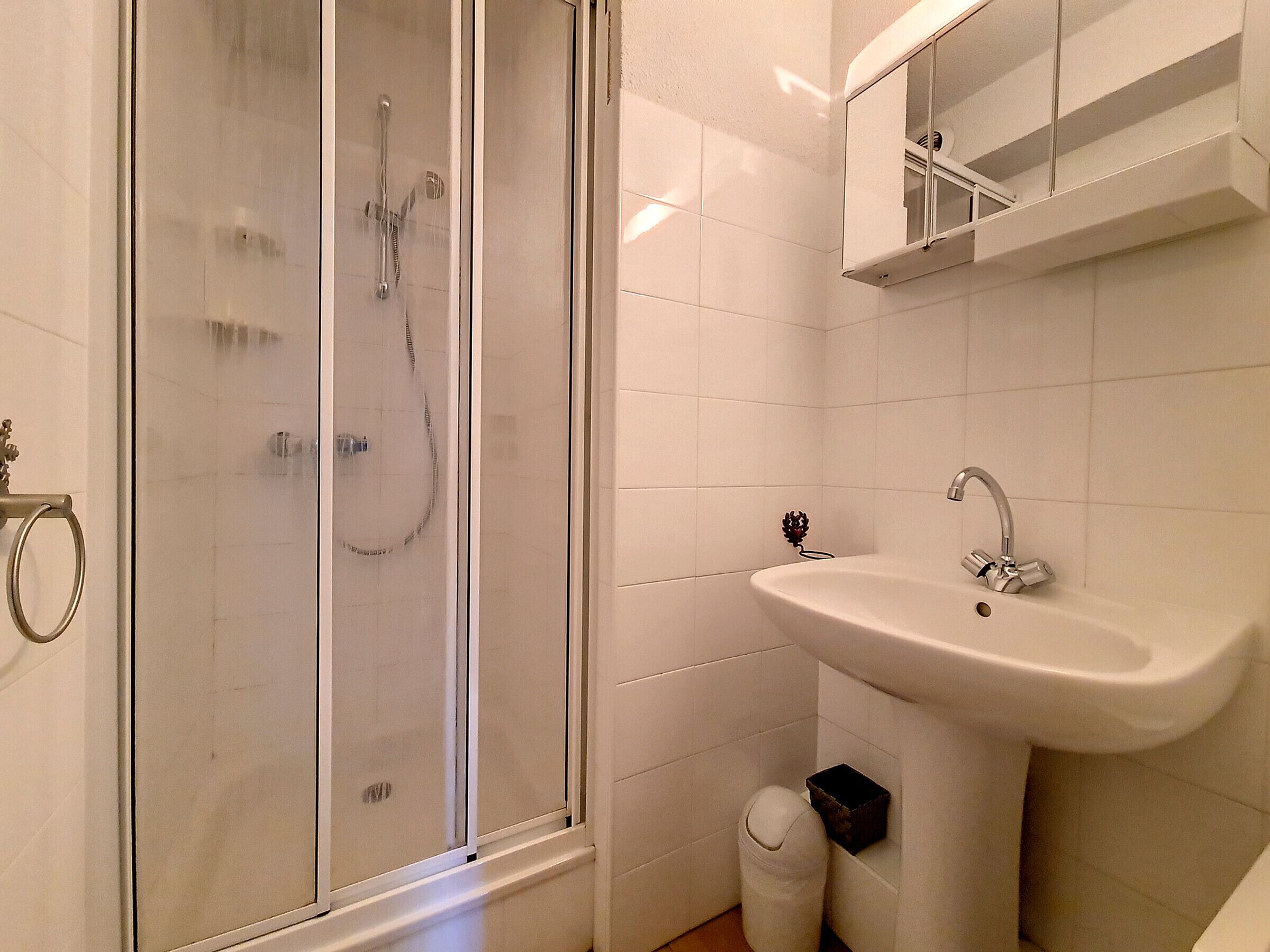 Een badkamer met een douche met glazen wand, een wastafel en een spiegel erboven.