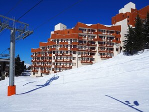 Ett hotell med flera våningar och balkonger, beläget på en snötäckt sluttning.
